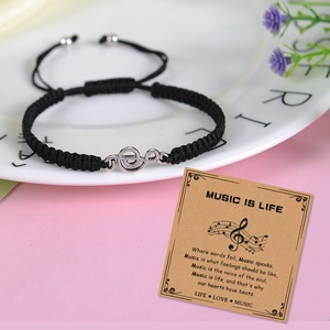 Adjustable black woven rope bracelet with silver treble clef charm on a music theme card