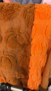 Close-up of heart-patterned brown plush fabric and orange faux fur texture for pillows