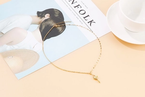 Flat lay of a gold heart-shaped key pendant necklace on a peach aesthetic background