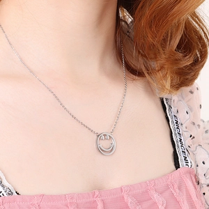 Gros plan d'un collier argenté avec pendentif visage souriant porté par un mannequin