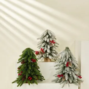 Miniature Christmas pine trees with snow flocking, red berries, and natural pinecones