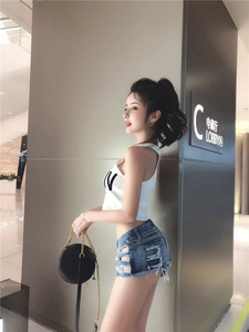 Dettaglio degli shorts in denim con ritagli laterali e bordi sfrangiati con crop top bianco