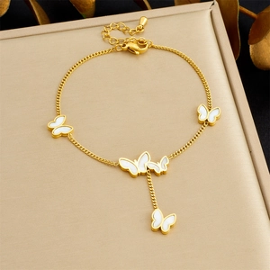 Detailed shot of golden butterfly chain bracelet with white shell flower pendants