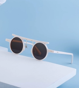 Detail of white round sunglasses with golden star accents and brown tinted lenses