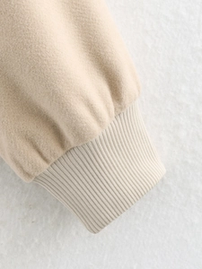 Detail of soft beige wool jacket featuring ribbed elastic cuffs and premium woven texture