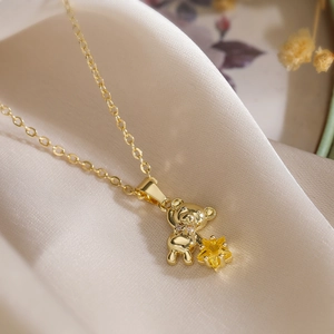 Gold bear pendant necklace with yellow star gemstone on elegant beige silk fabric