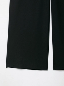Dettaglio dell'orlo dei pantaloni neri che mostra la trama del tessuto in twill pregiato