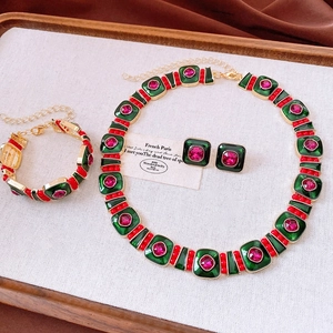 Dettaglio di un set di gioielli vintage con smalto verde e cristalli rosa dorati