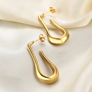 Detailed view of polished 14K gold-plated teardrop earrings on white silk fabric