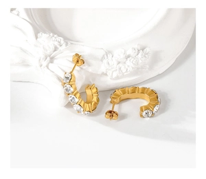 Detail view of gold C-shaped earrings with clear cubic zirconia in a prong setting