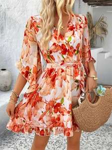 Detailed view of the V-neck and orange floral print on a white chiffon wrap dress