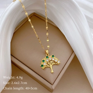 Detailed view of a gold tree of life necklace with green and white gems on a jewelry box