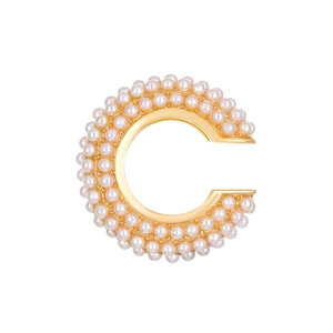 Detail of C-shaped gold ear cuffs set with elegant white pearls on a polished base