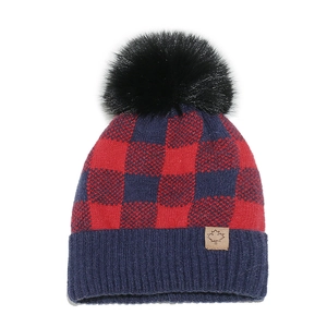 Detail of red and blue buffalo plaid knit beanie with large faux fur pompom and leather patch