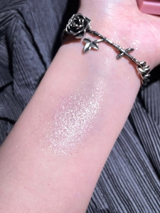 Arm swatches of shimmer pink-purple eyeshadow palette with glitter texture and rose bracelet
