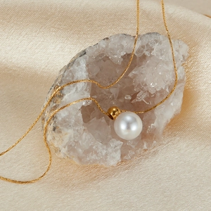 Close-up of a white pearl pendant on a gold necklace over a white crystal cluster
