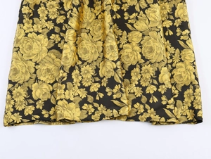 Primer plano detallado de la tela jacquard floral negra y dorada con textura brocada