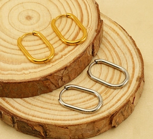 Macro detail of oval hoop earrings in gold and silver finish on a wooden display