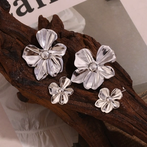 Detailed view of silver stainless steel petal earrings in two sizes on wood display