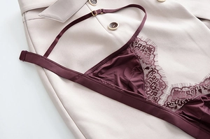 Dettaglio intimo in pizzo bordeaux con bordo a ciglia su sfondo blazer beige