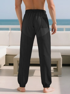 Detail of men's black sweatpants featuring fabric texture and functional back pocket design