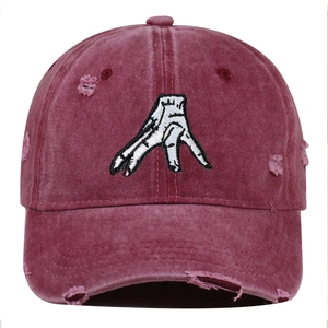 Detail of distressed burgundy baseball cap featuring white palm embroidery and worn edges