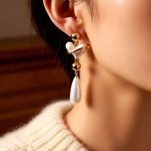 Close-up of vintage heart pearl drop earrings with gold metal ring on female model