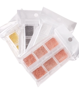 Macro detail of mixed size metal caviar beads for nail art in six-compartment plastic cases