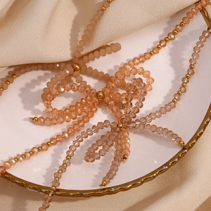 Detailed macro view of handmade champagne crystal bow pendant on a stainless steel bead chain