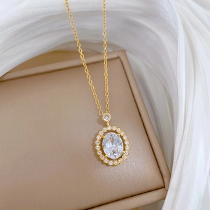 Detailed view of an oval zircon pendant with gold finish on a beige jewelry display