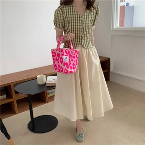Lifestyle shot of pink leopard print tote bag with green plaid top and white midi skirt