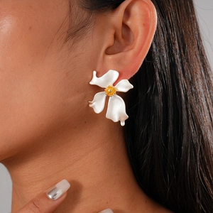 Nahaufnahme von Vintage-Blumenohrringen mit mattweißen Blüten und goldener Mitte