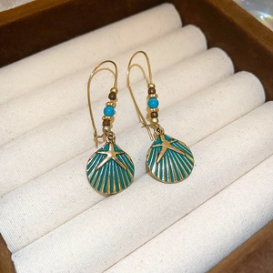 Macro shot of bohemian seashell earrings with teal enamel, starfish detail and beads