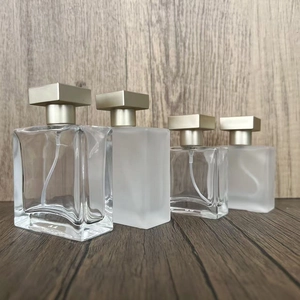 Square glass perfume bottles in clear and frosted finish with gold caps on wood