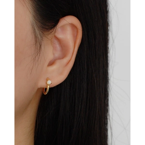 Close-up of minimalist gold hoop earring featuring an elegant white opal inlay on model