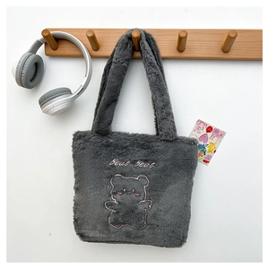 Gros plan d'un sac cabas en peluche gris foncé avec motif d'ours rose brodé