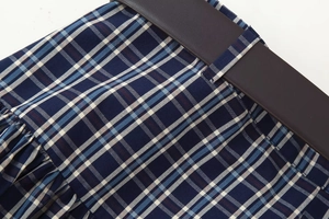Detailansicht des dunkelblauen Karo-Midirocks mit einem breiten dunkelbraunen Gürtel aus Leder