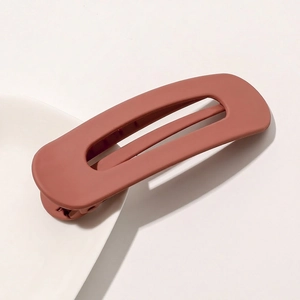 Detail view of large matte brick red hair clip with hollow rectangular design and duckbill clip