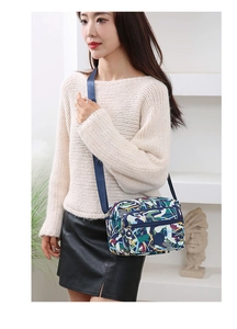 Detail view of colorful printed crossbody bag with multi-zipper layers on a female model