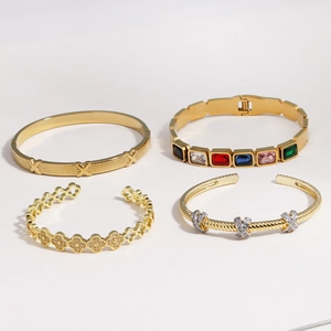 Détails de quatre bracelets en acier titane doré avec gemmes colorées et trèfle
