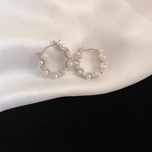 Elegant wavy silver hoop earrings with white pearls and small diamonds on white silk
