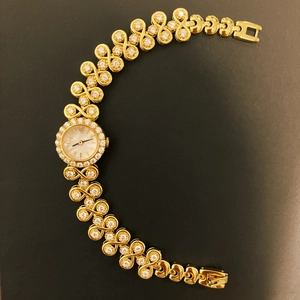 Luxury vintage gold watch for women with rhinestone-studded bracelet on black background