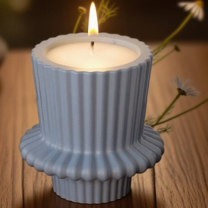 Detailed view of striped blue candle holder on a dark wooden table with white daisies