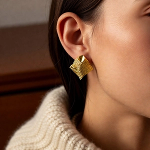 Close-up detail of vintage 18k gold plated rhombus tassel earring worn by a model