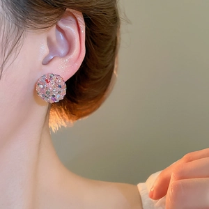 Close-up of a sparkling spherical earring with colorful rhinestones on a female model