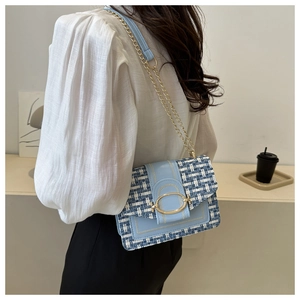 Blau-weiße Tweed-Umhängetasche mit goldener Kette am Model für den täglichen Weg zur Arbeit