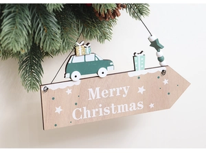 Gros plan d'une plaque flèche en bois Joyeux Noël avec décor de voiture sur un sapin