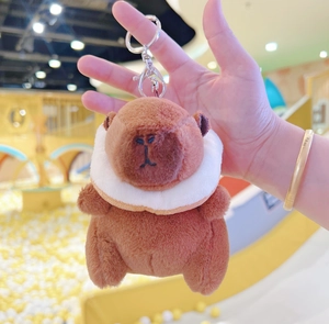 Close-up of brown plush capybara keychain with white scarf and silver metal clasp