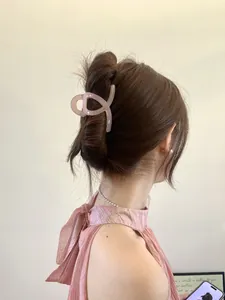 Détail de la grande pince à cheveux rose clair sur un chignon élégant avec lumière douce