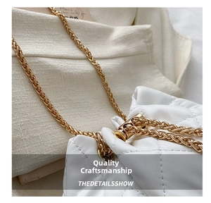 Close-up of white quilted leather bucket bag with gold chain and drawstring metal lock